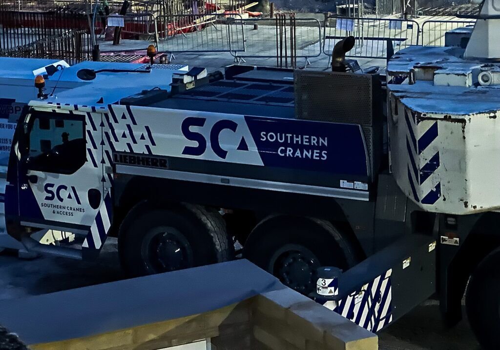Mobile crane Liebherr mengangkat material di area konstruksi gedung